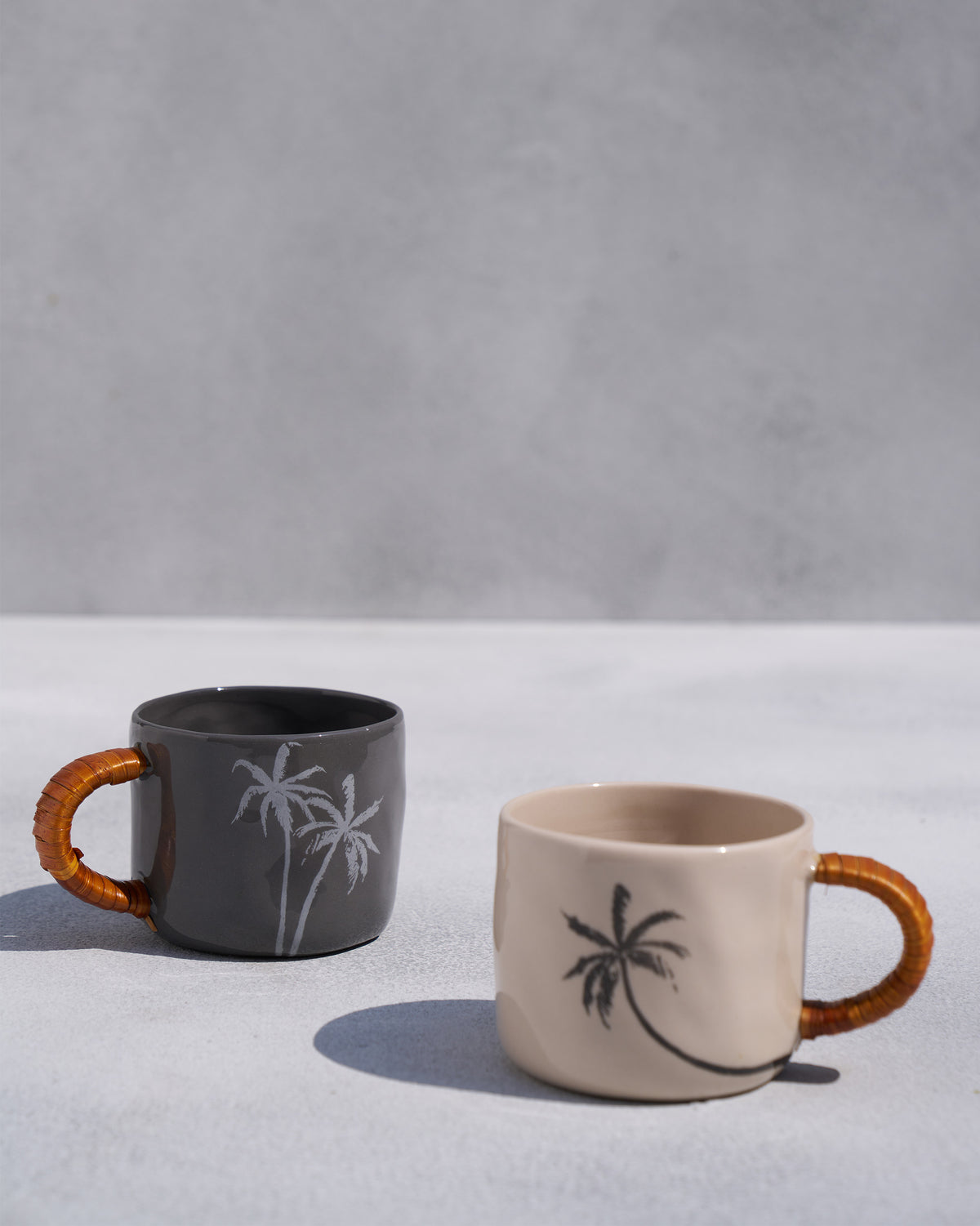 Pair of Mandovi mugs in charcoal and ivory with palm tree prints.