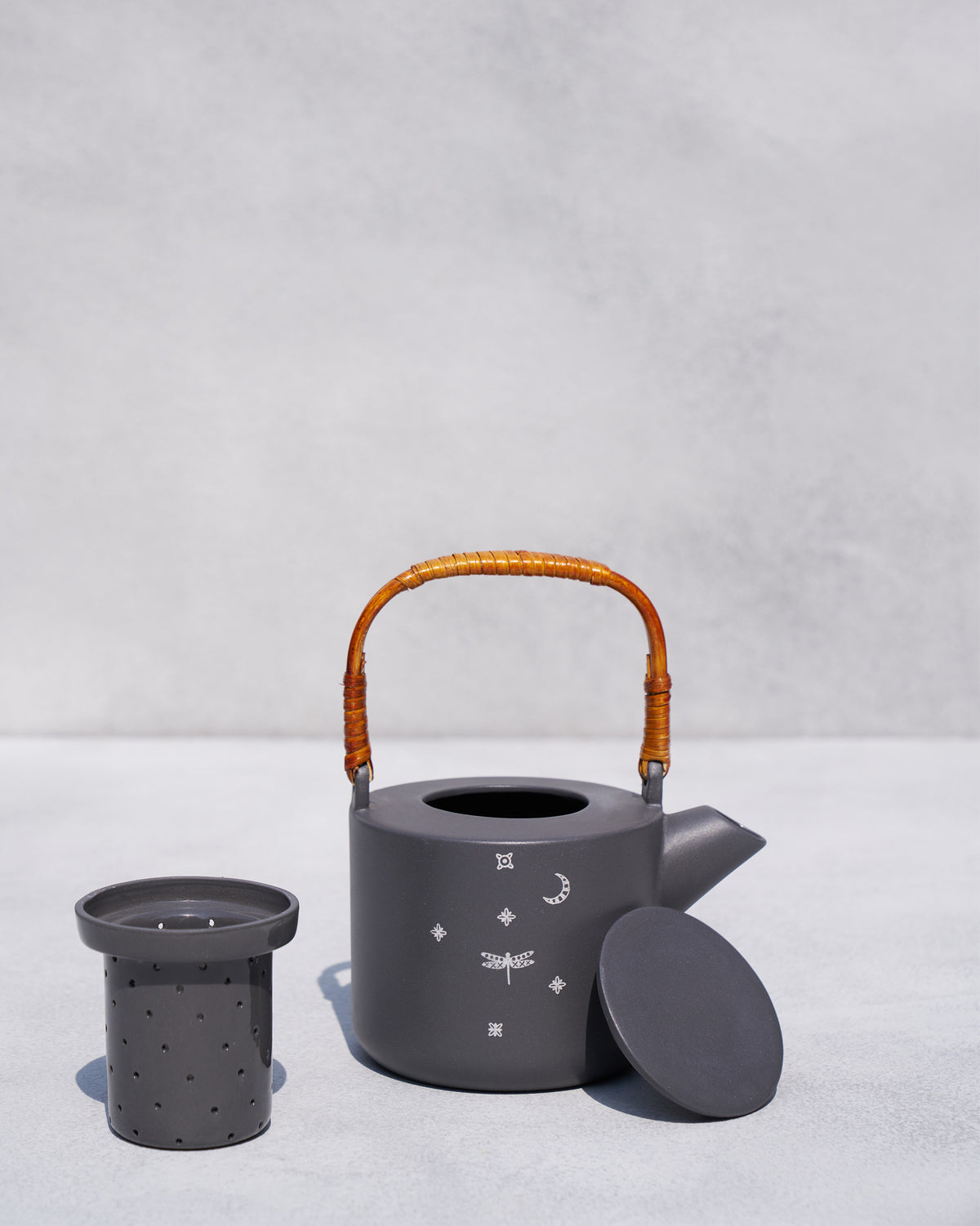 Taramandal teapot open beside its perforated ceramic infuser.