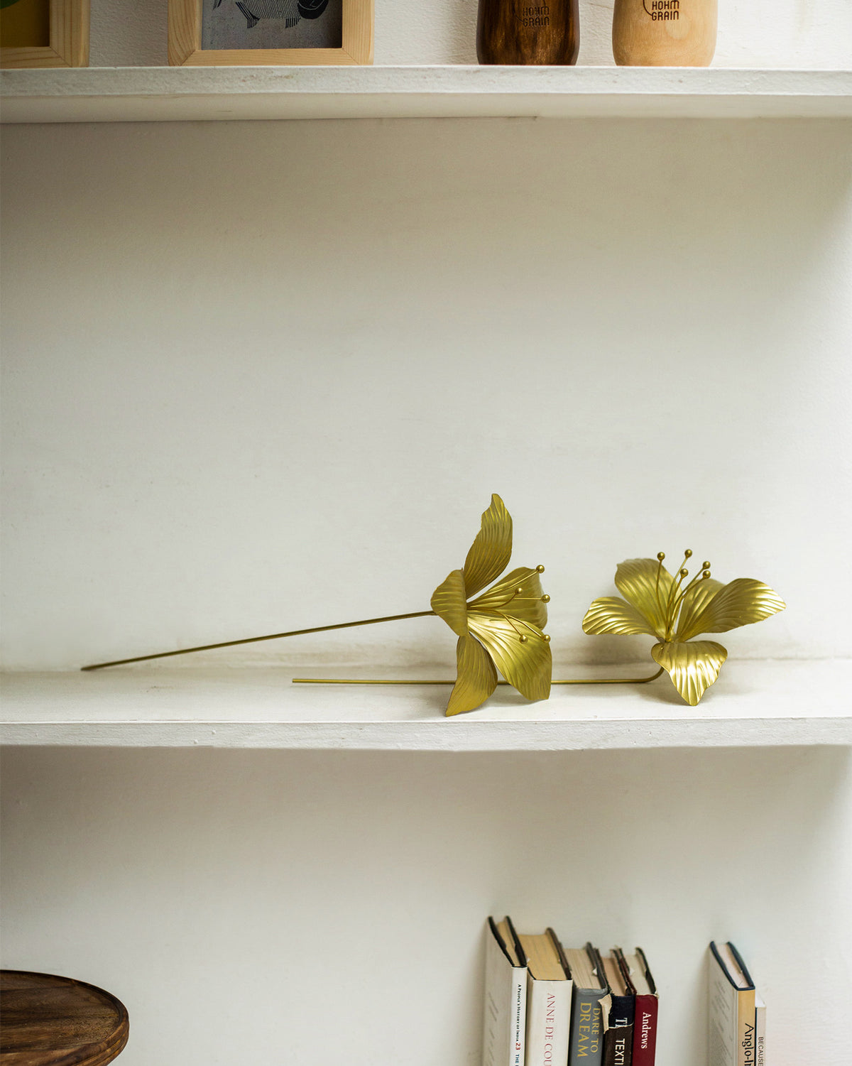 Two gold Kachnar flower accents with long stems on a shelf.