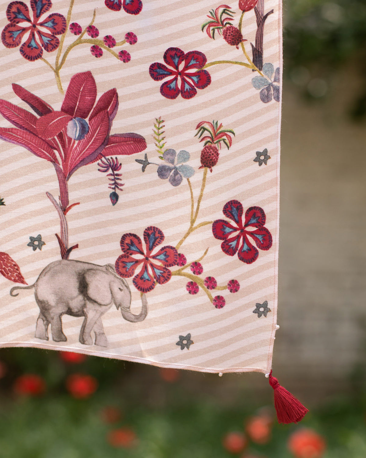 Close-up of the Cascade Scarf showing a grey elephant and a red tassel.