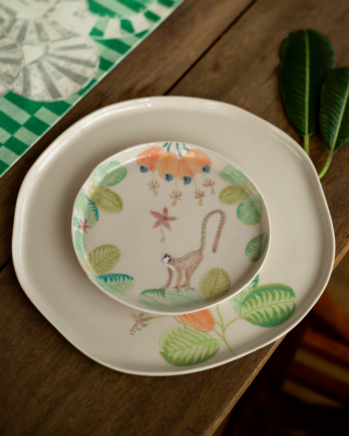 Mandovi dessert plate nested on a larger leaf-and-fruit dinner plate.