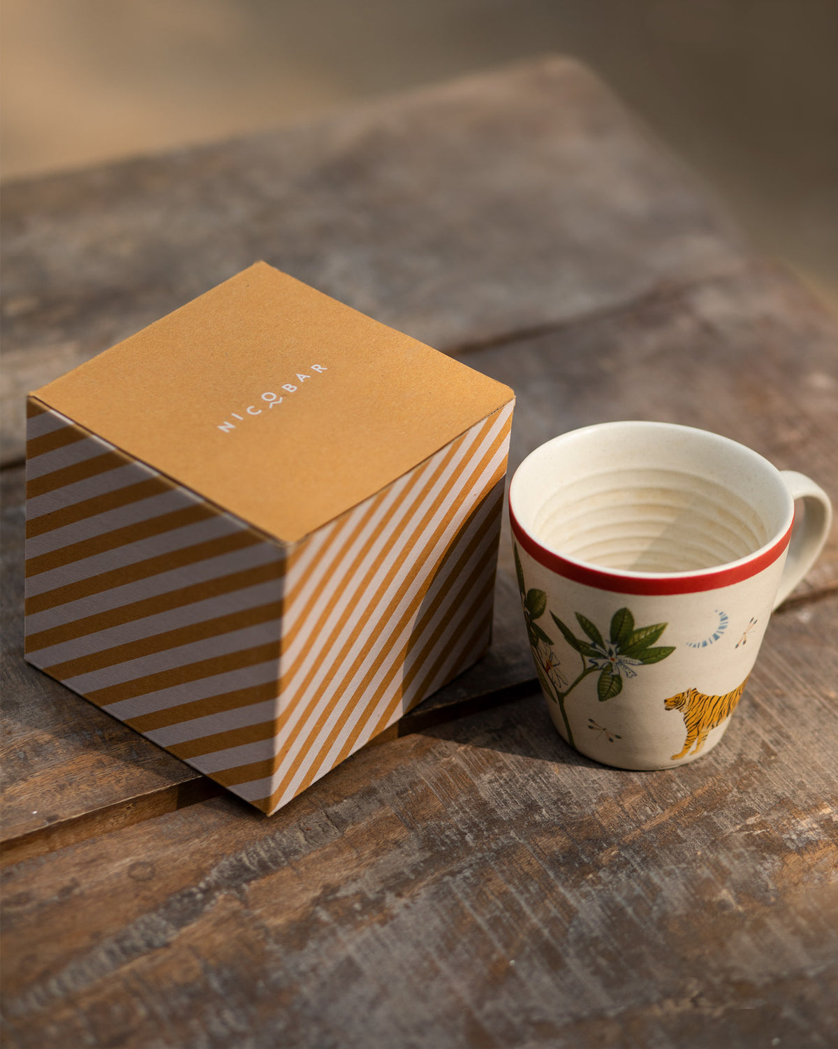 Nadi conical mug with tiger print beside its mustard striped Nicobar gift box.