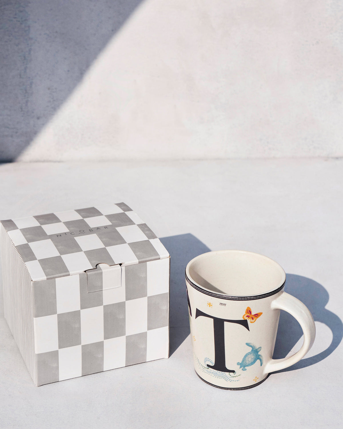 Tara mug beside its grey and white checked gift box.