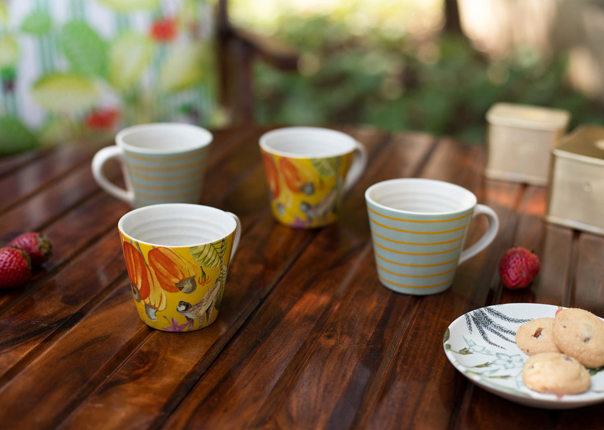 Four Mahi espresso mugs with monkey and stripe designs on a table.