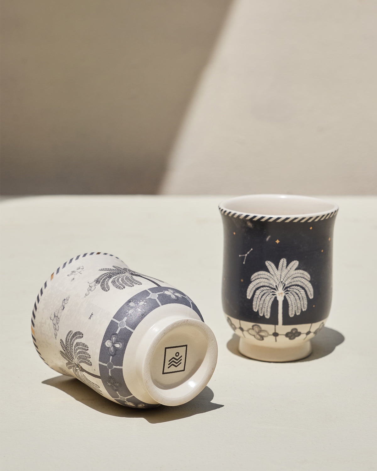 Cream Twilight Tea Cup turned over to show its base stamp, beside a navy cup.