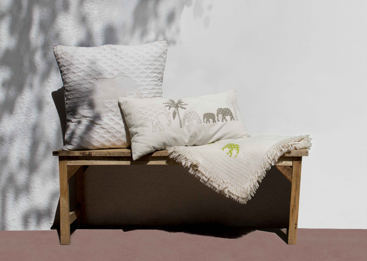 Ele Palm lumbar cushion cover on a wooden bench beside a throw.