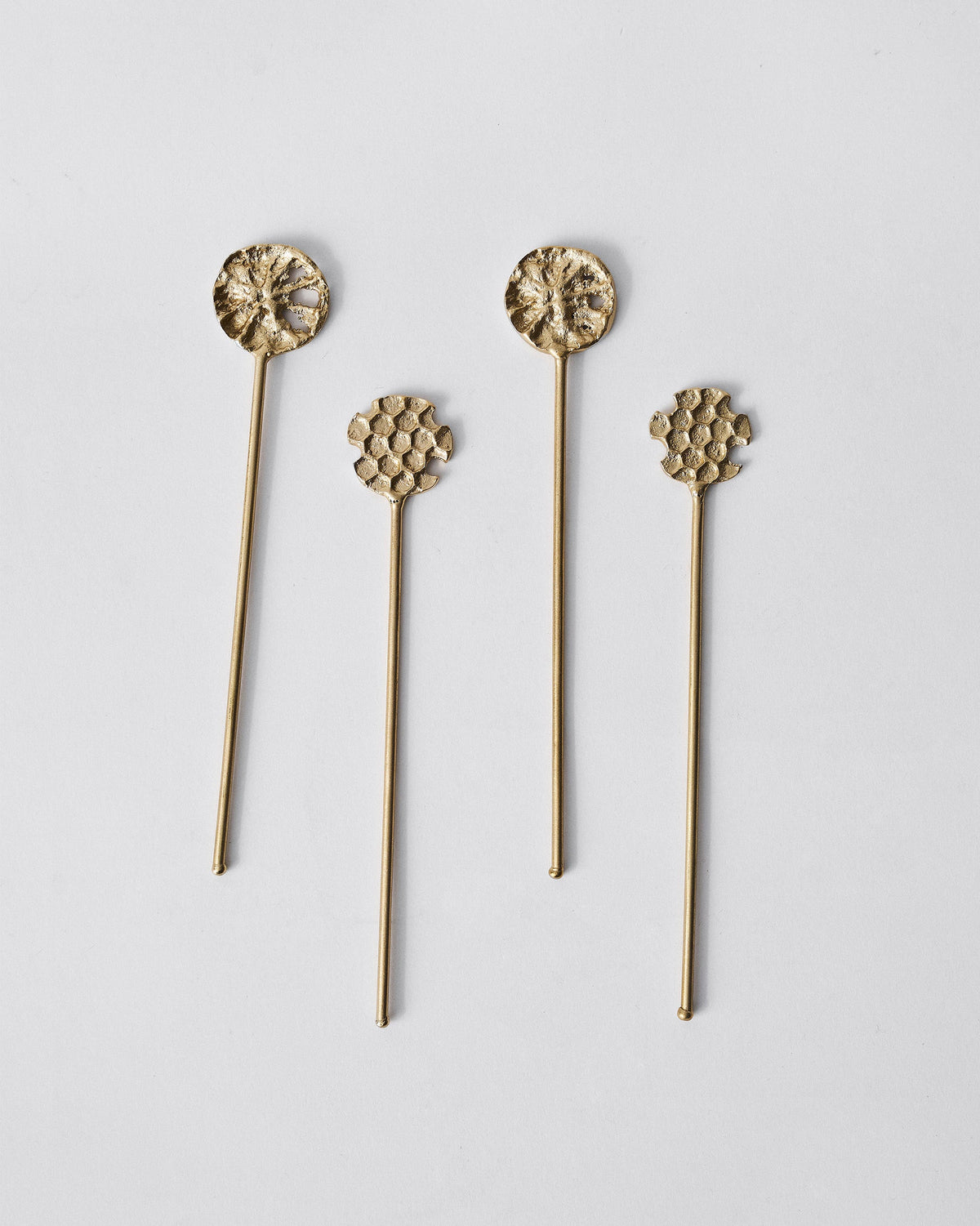 Pair of floral and honeycomb gold Dawa stirrers laid flat side by side.
