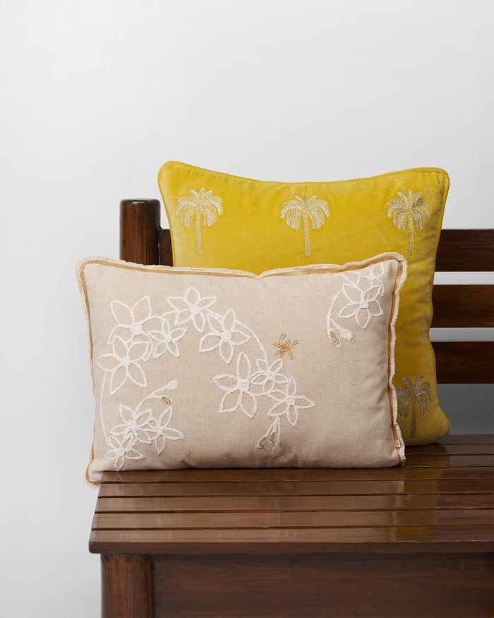Madhu cushion cover with white embroidered flowers and a bee.