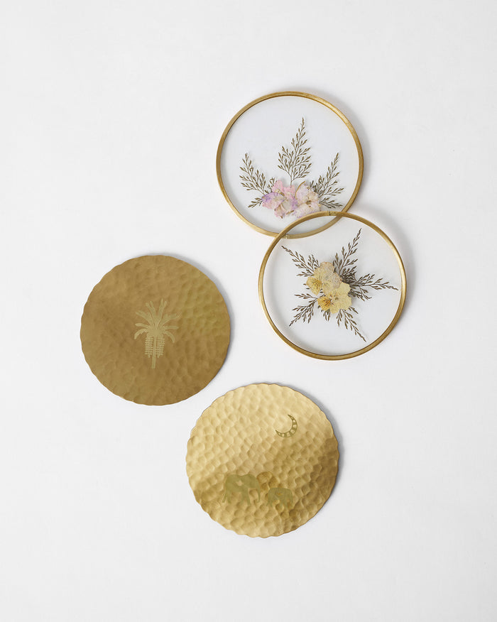 Palm Grove set of four coasters: brass palm and elephant designs plus pressed-flower glass.