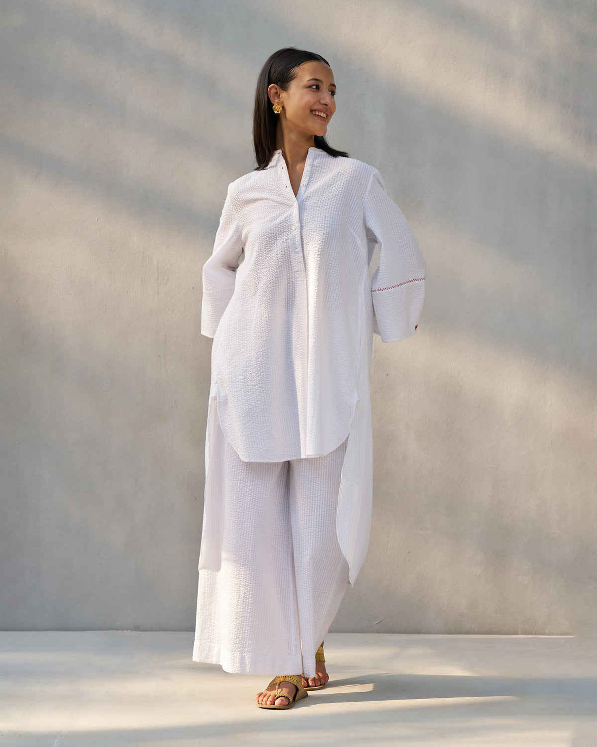 Person wearing white seersucker Basic Pyjamas with a matching high-low tunic.