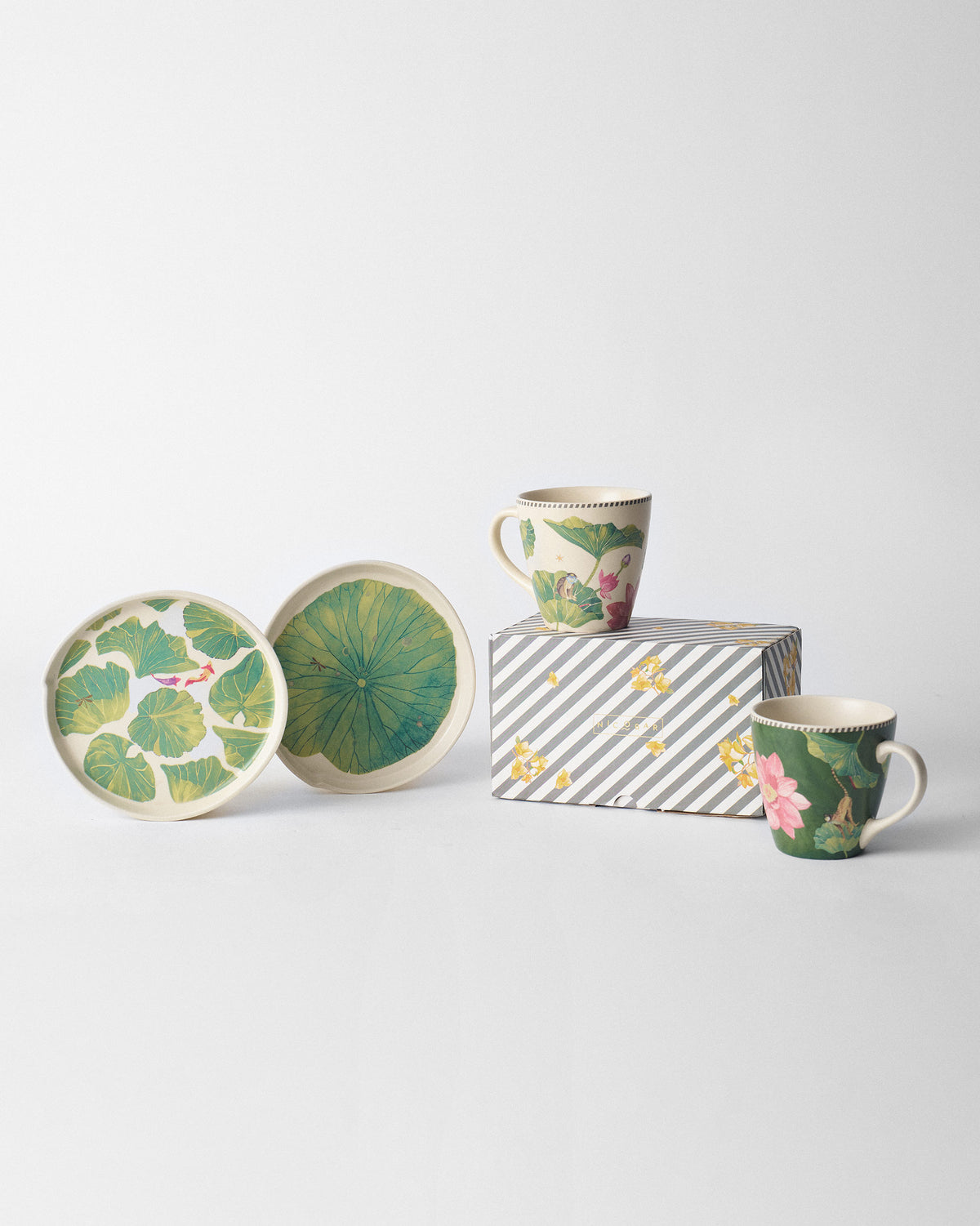 Lotus Garden Dessert Plates beside lotus mugs and a striped box.