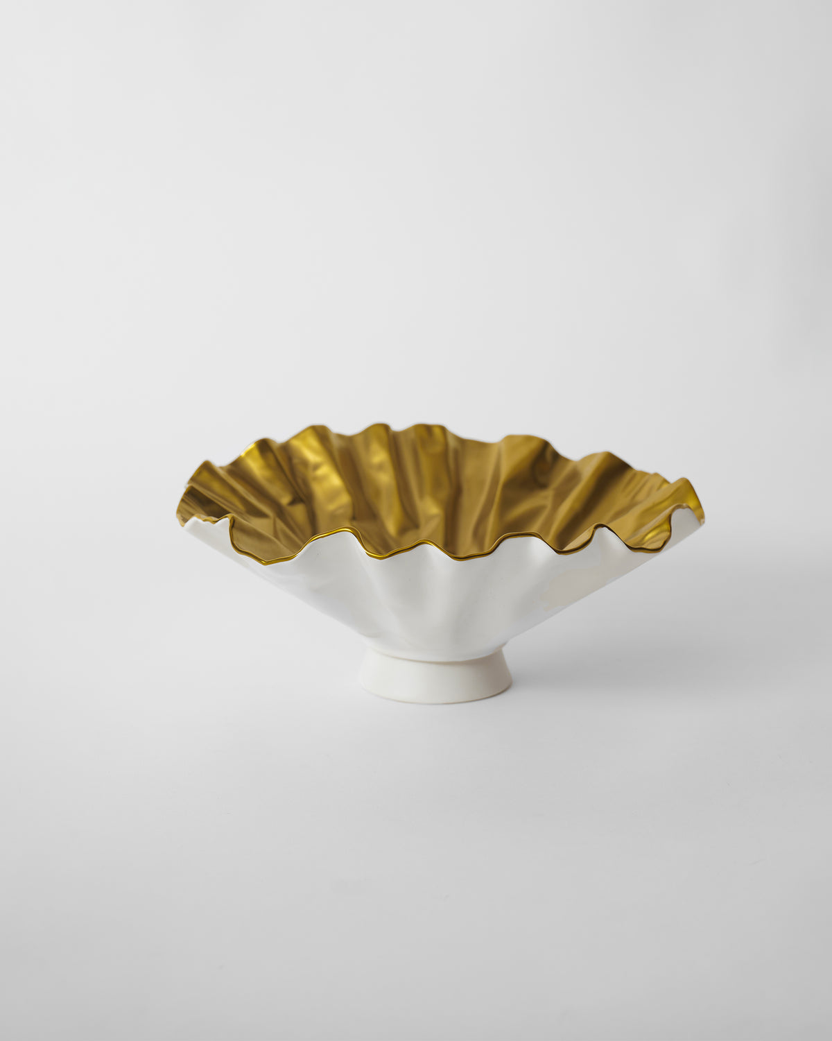 Dhaara Fruit Bowl in white with a ruffled gold interior on a small pedestal.