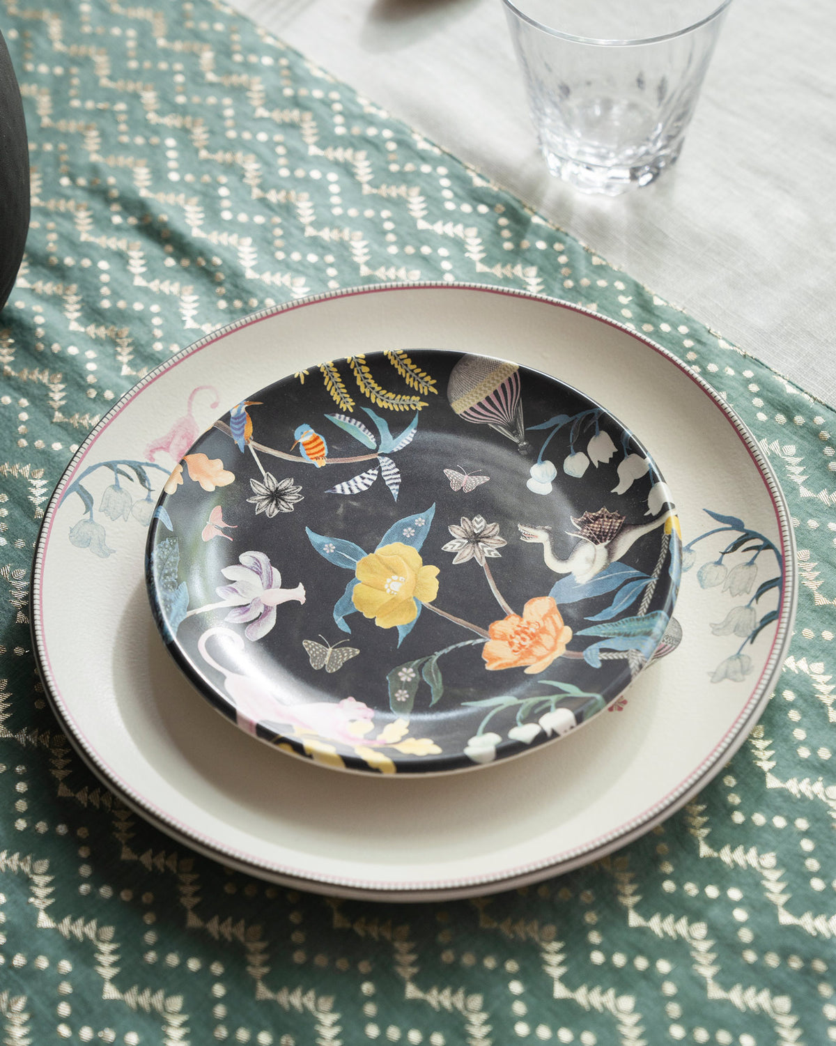 Charcoal Myra quarter plate with yellow flowers and birds stacked on a cream dinner plate.