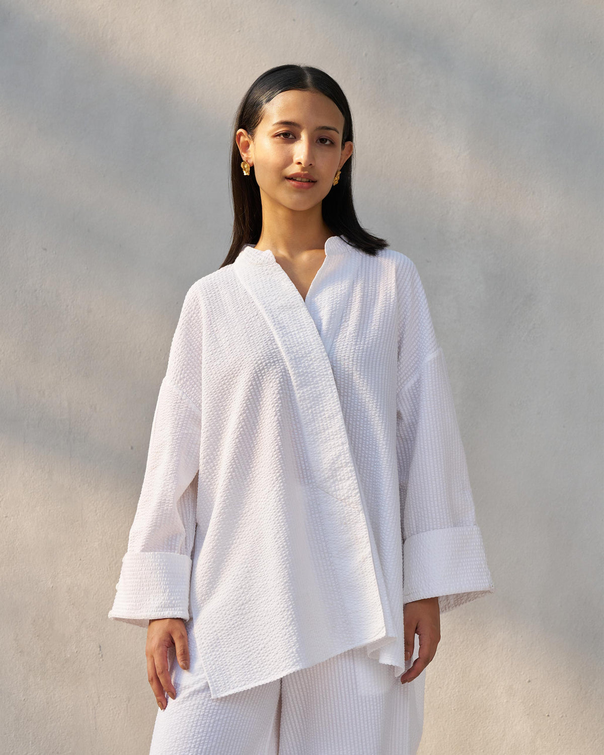 Person wearing a white seersucker Cirrus shirt with wide fold-over cuffs.