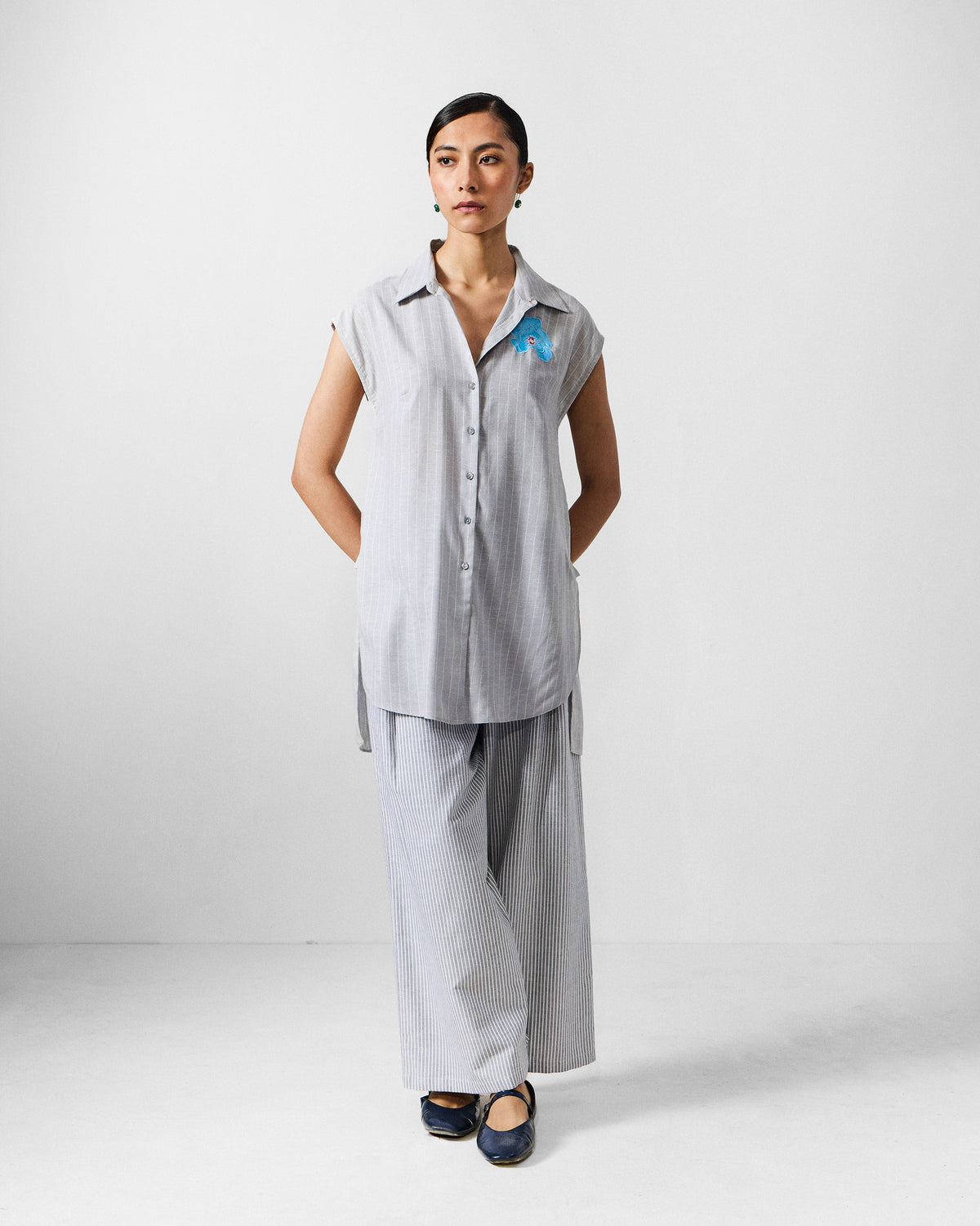 Person wearing a grey and white striped sleeveless tunic.