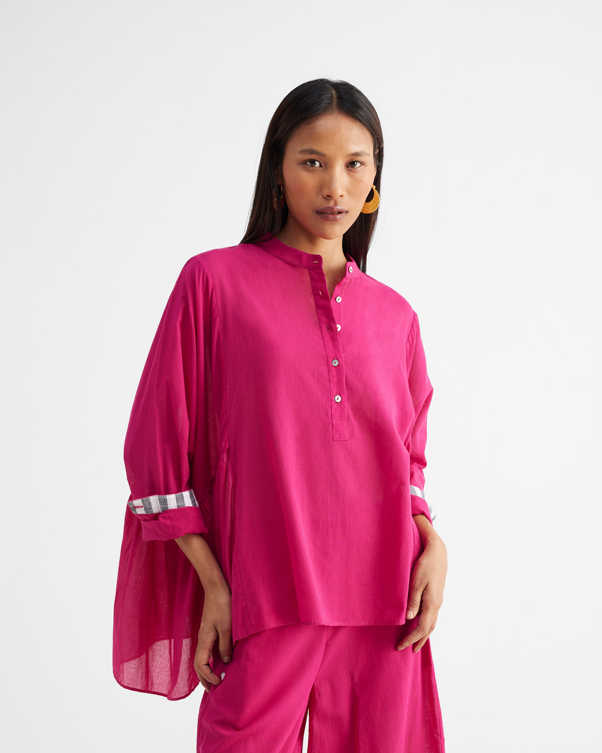 Front of a fuchsia Dolman Top with a button placket and checked sleeve cuff.