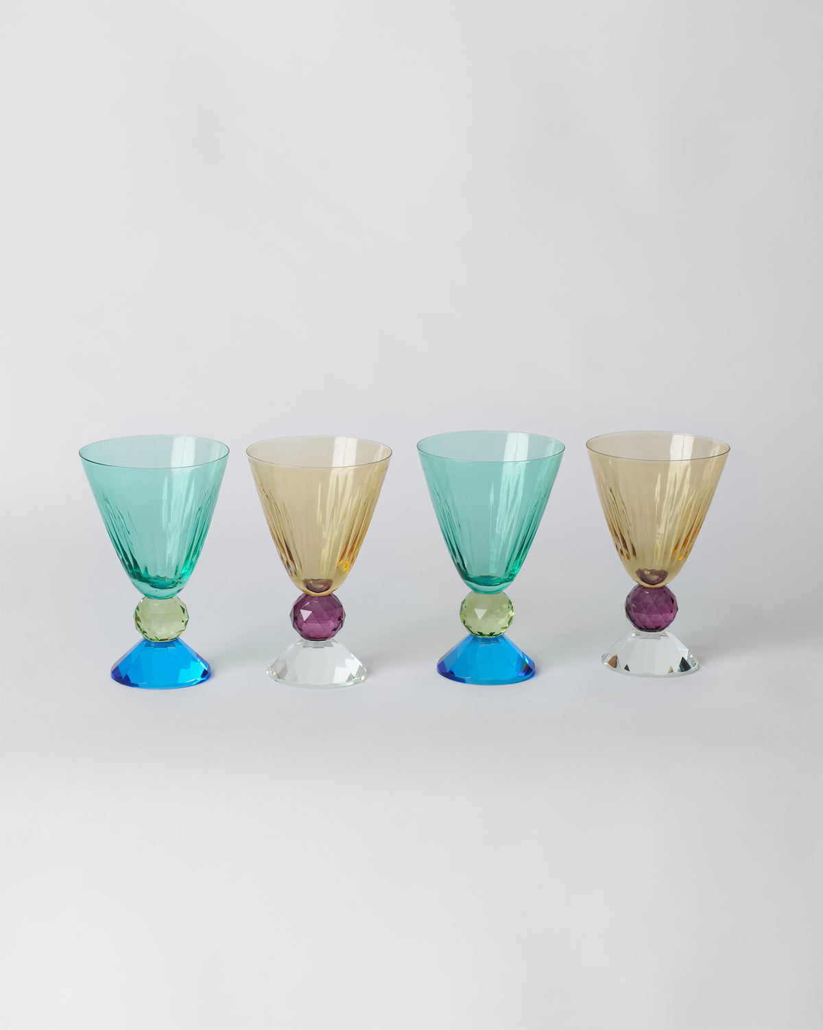 Row of four Vira cocktail glasses in teal and amber colourways.