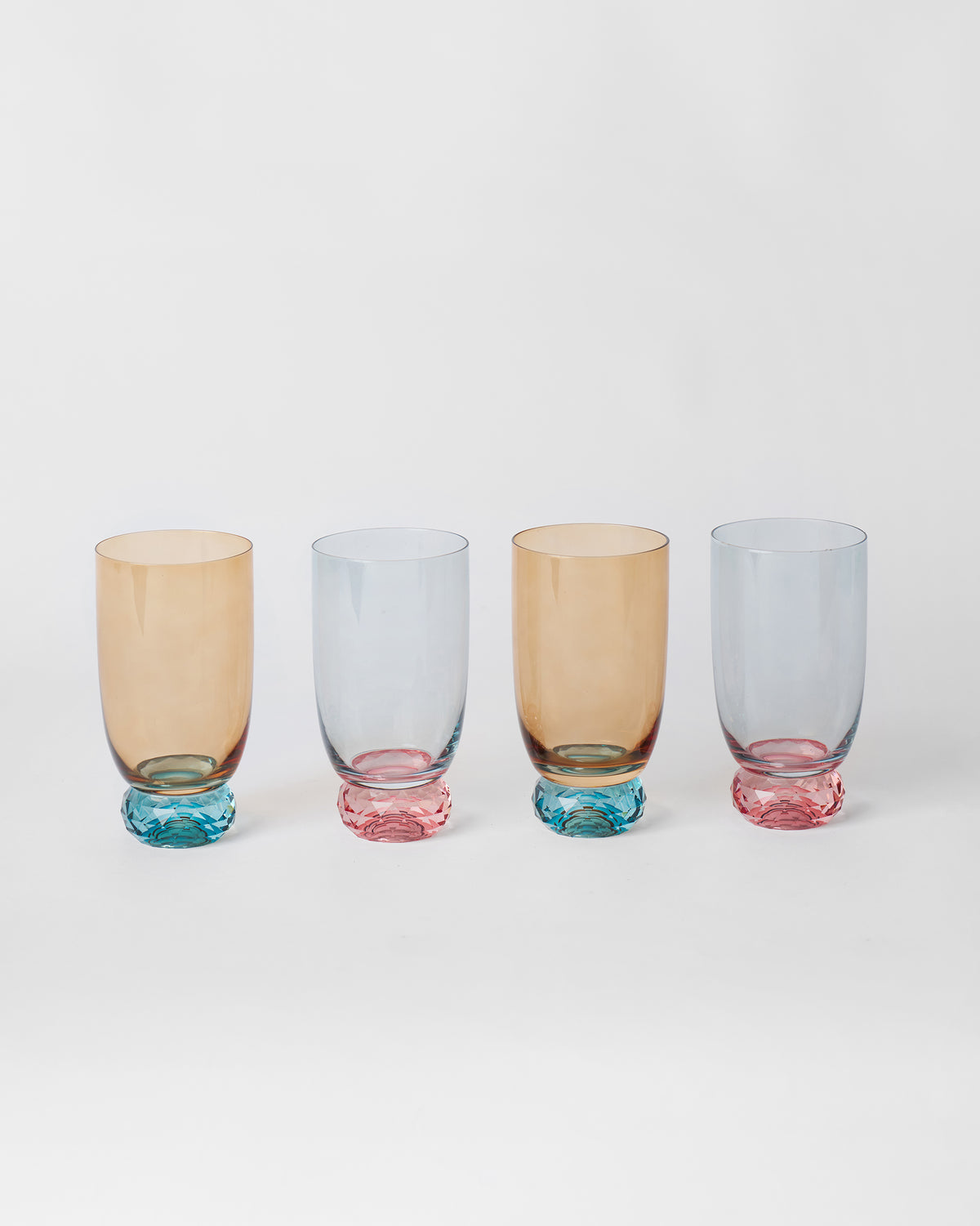 Row of four Reva sharbat glasses with teal and pink faceted bases.