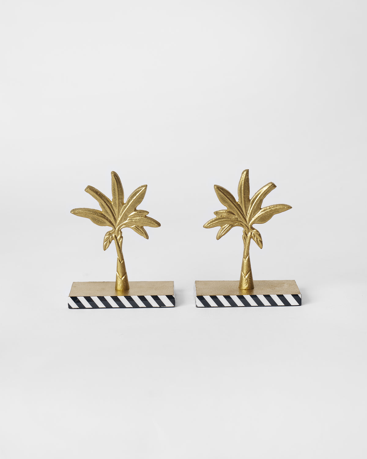 Pair of Gilded Palm bookends with gold palm trees on black-and-white striped bases.