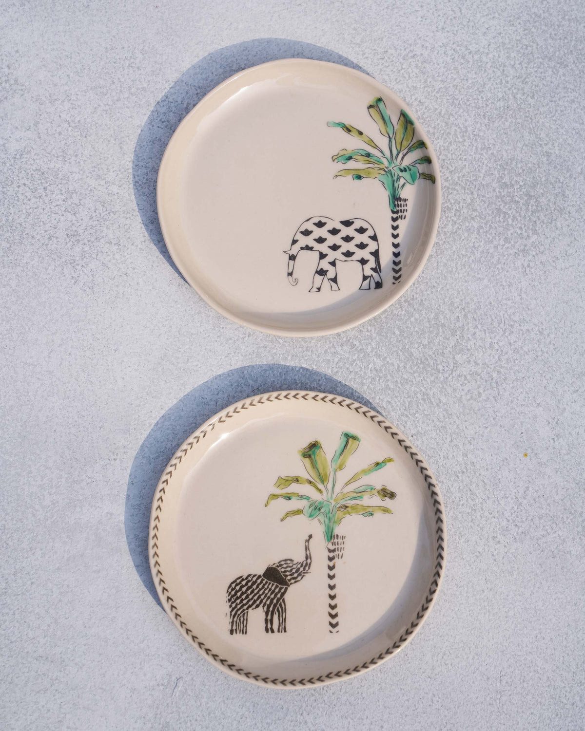 The pair of ivory Coastal Tea Plates with elephant and palm prints.