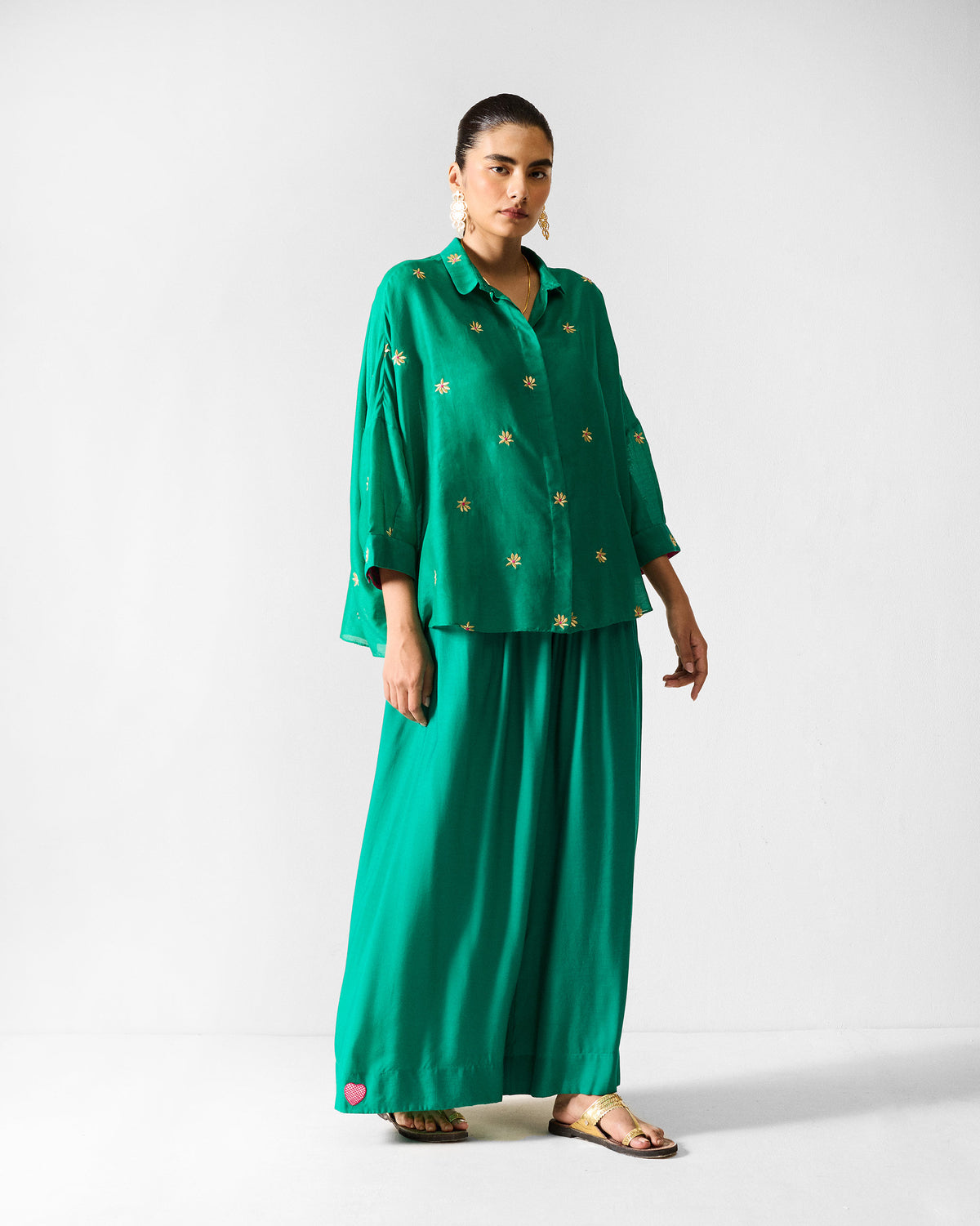 Person wearing green paperbag pants with a heart at the hem, shown full-length.