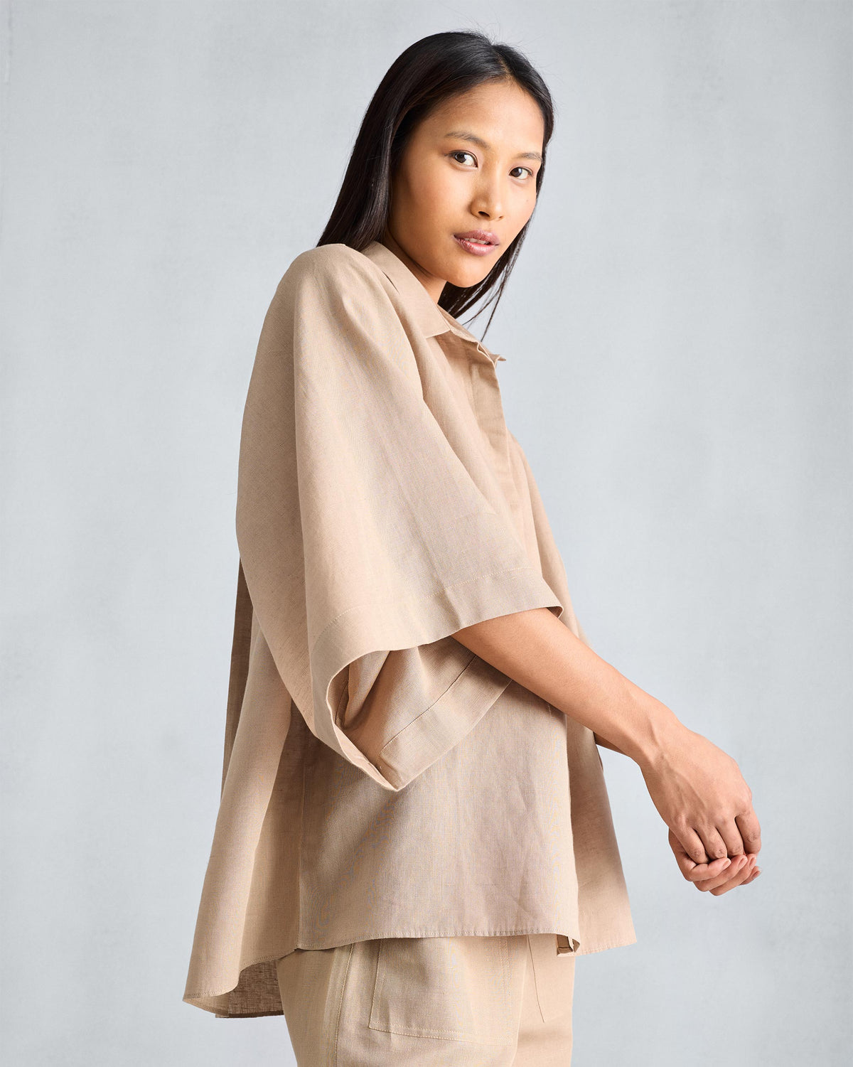 Beige Drop Armhole shirt with wide kimono sleeves, worn looking over the shoulder.
