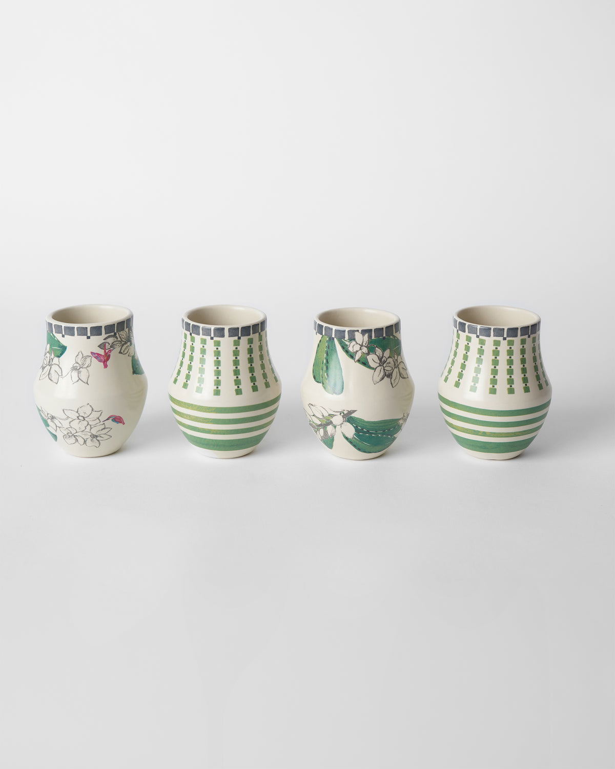 Four Reesha kulhars lined up, alternating floral and geometric green designs.
