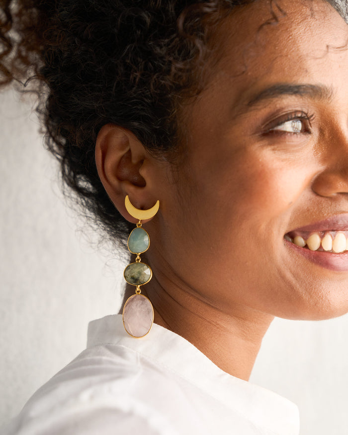 Side profile of Rosy Moon Earrings with a gold crescent and long drops on a person.