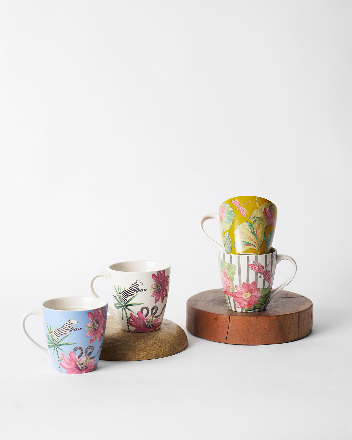 Wilderness mug set with lemur, zebra, lotus, and dragonfly designs on wood stands.