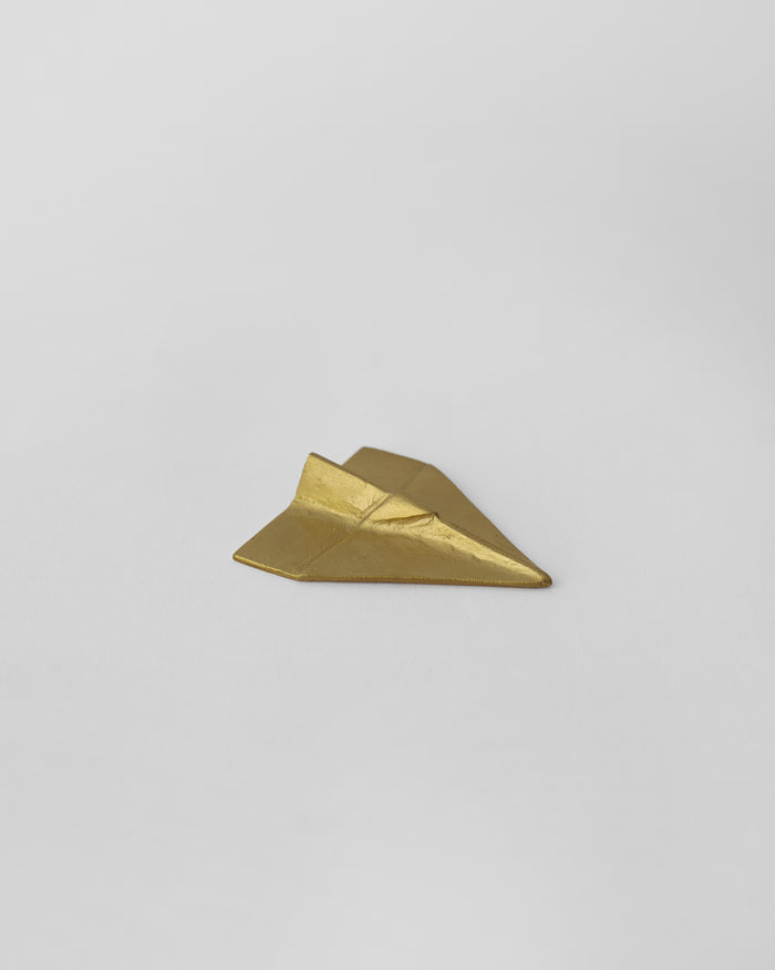 Flight Origami in gold, shaped like a folded paper plane.