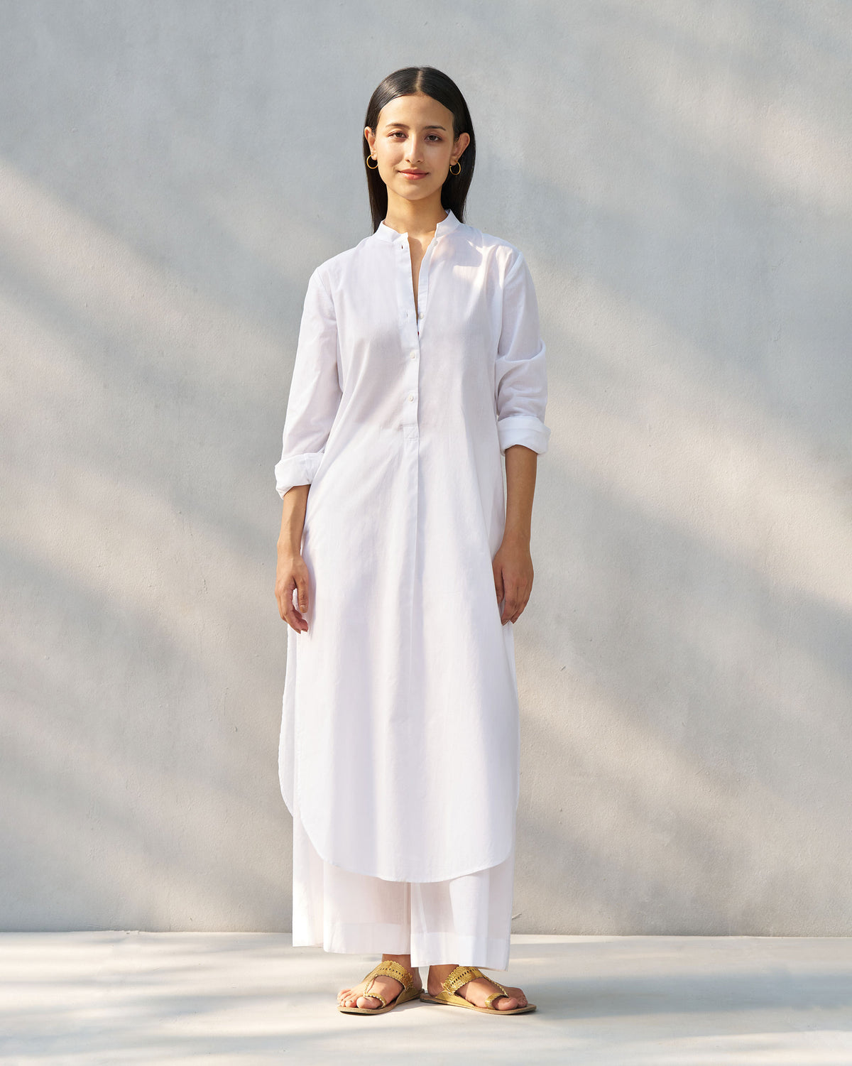 Person wearing a white long kurta set with matching wide-leg pants.