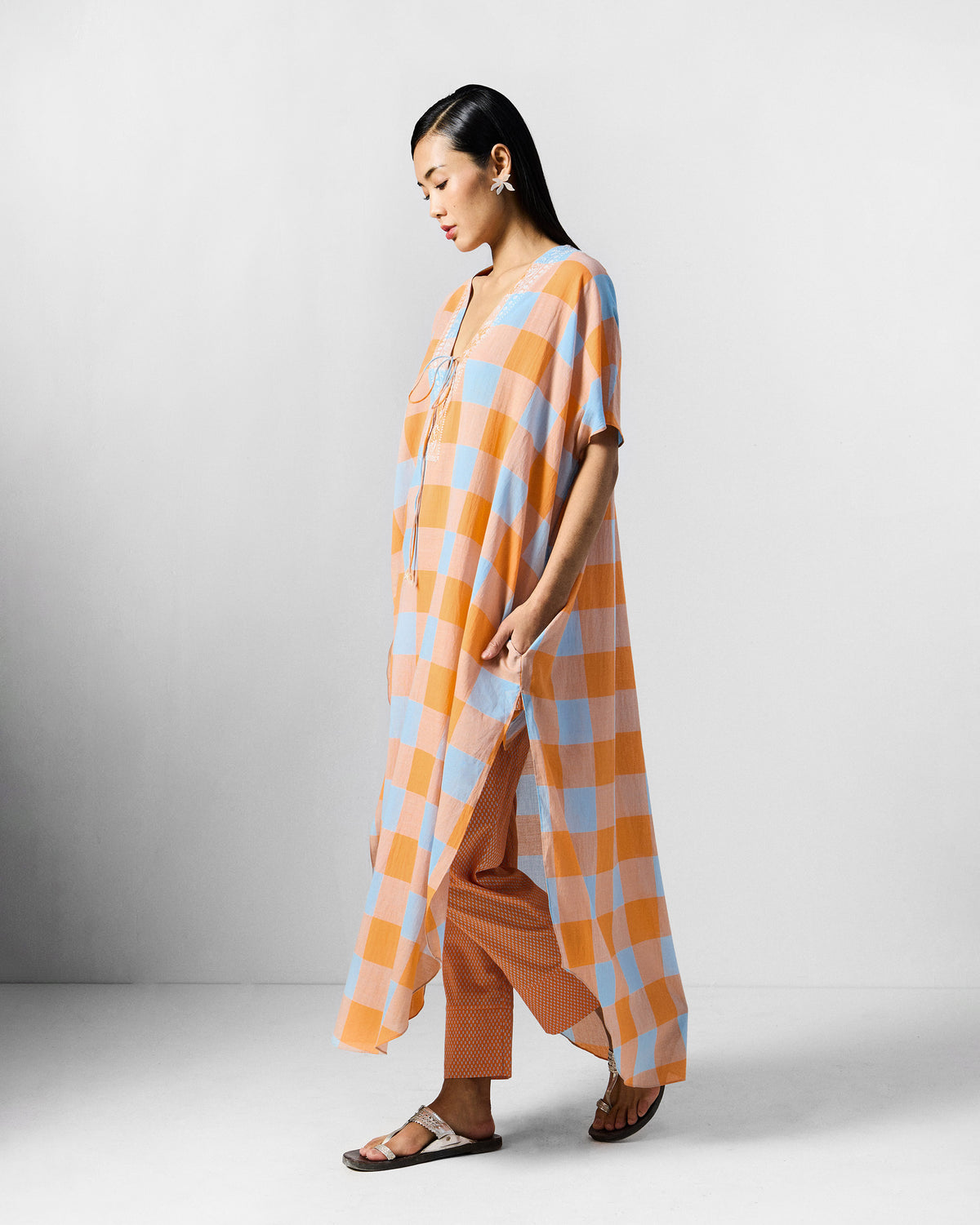 Side view of an orange and blue check Vaya kaftan with high side slits.