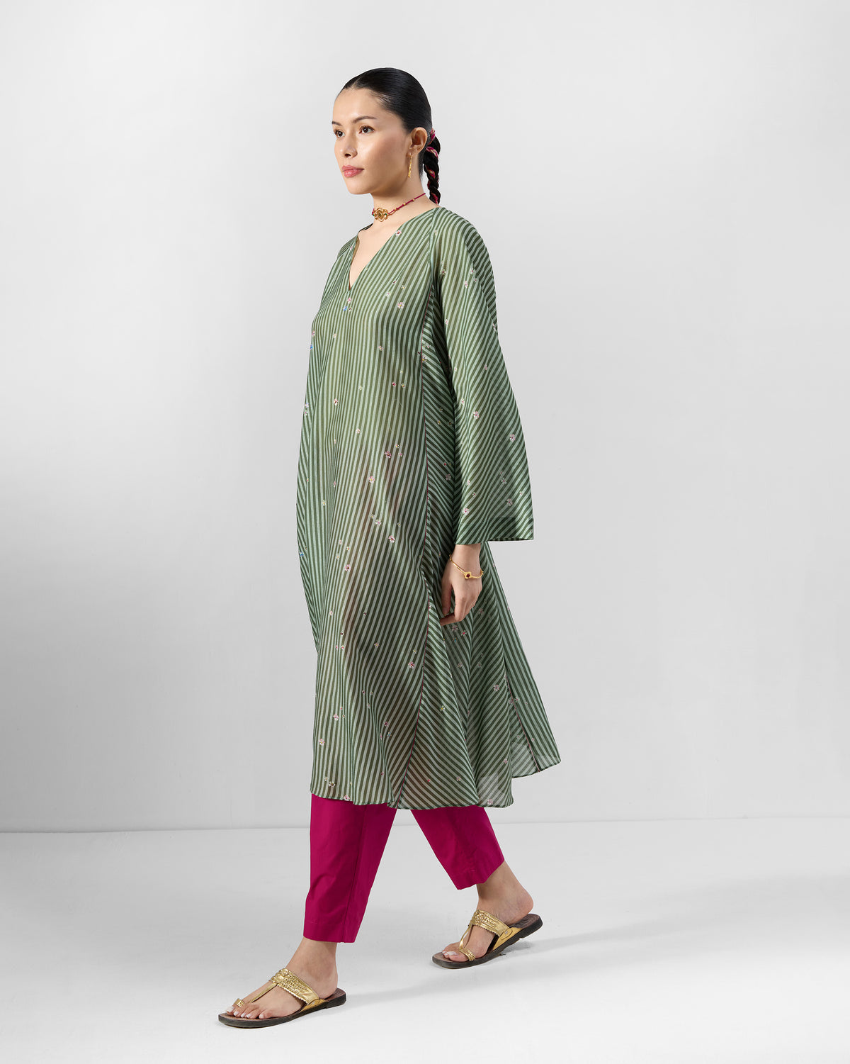 Person wearing a green and soft pink striped A-line Kutch kurta with scattered floral motifs.