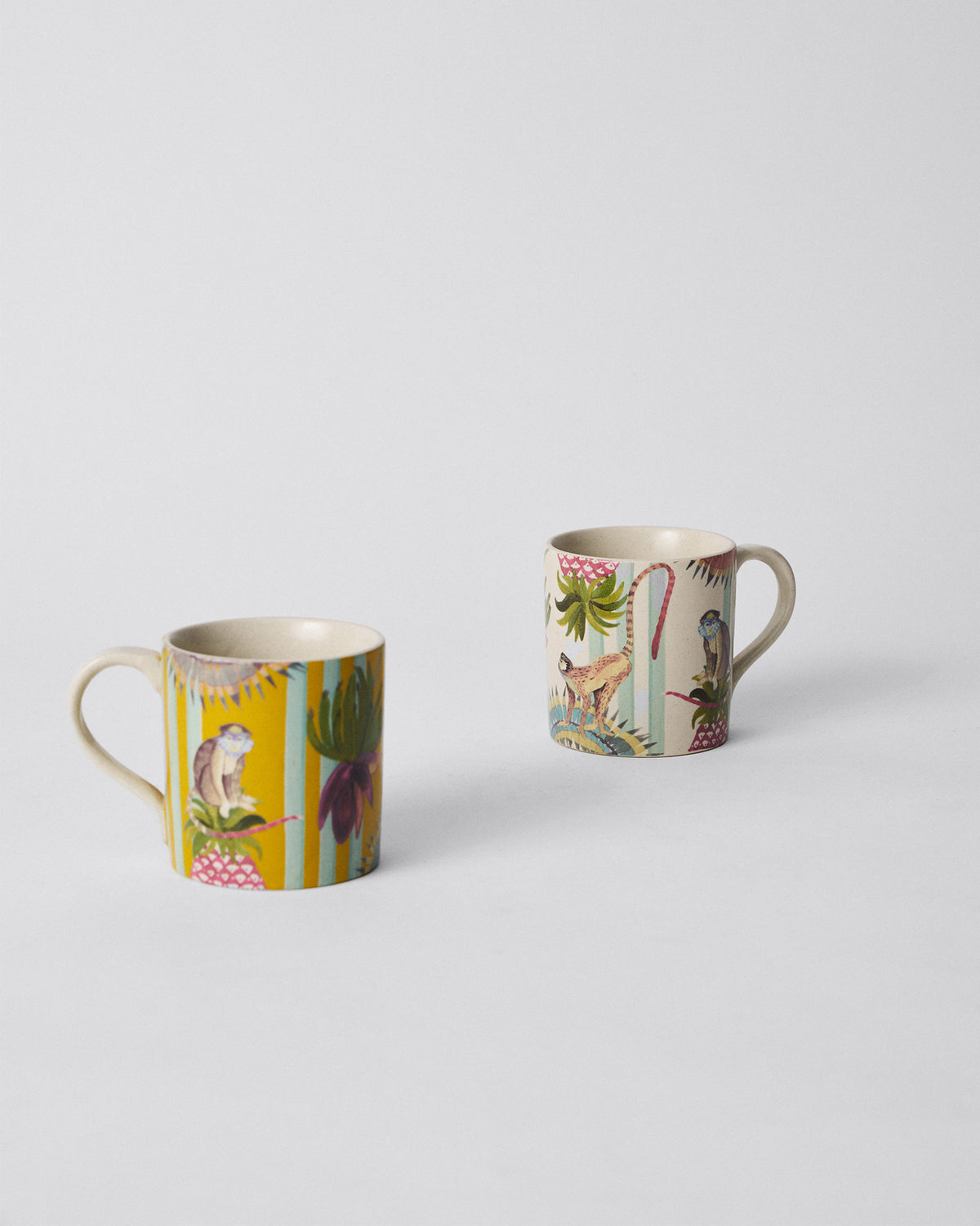 Yellow mug and ivory mug from the Mahi Mug Set, set apart on a plain surface.