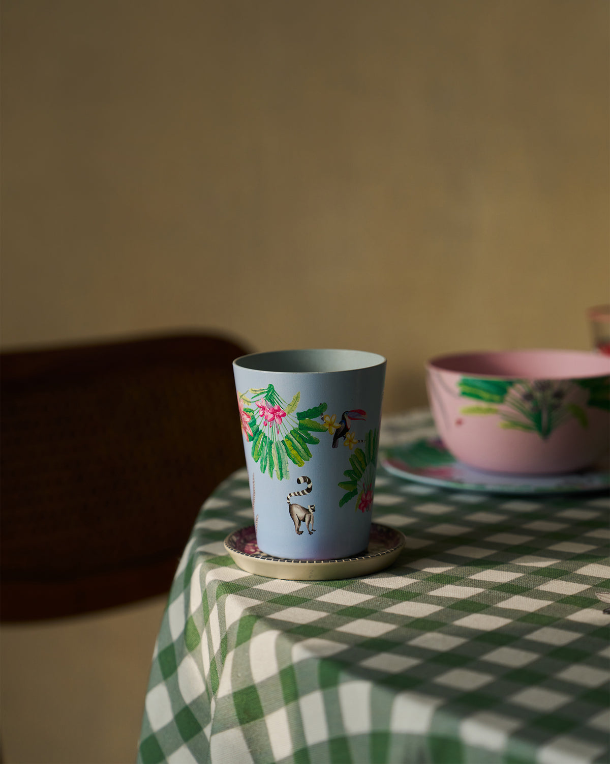 Dusty blue Toucan bamboo tumbler on a saucer with a matching pink bowl behind.