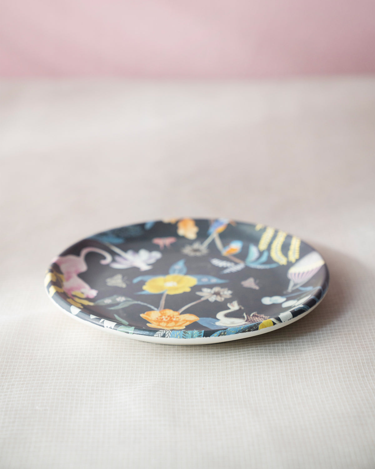 Charcoal Myra quarter plate with a pink leopard and yellow flowers on a dark ground.