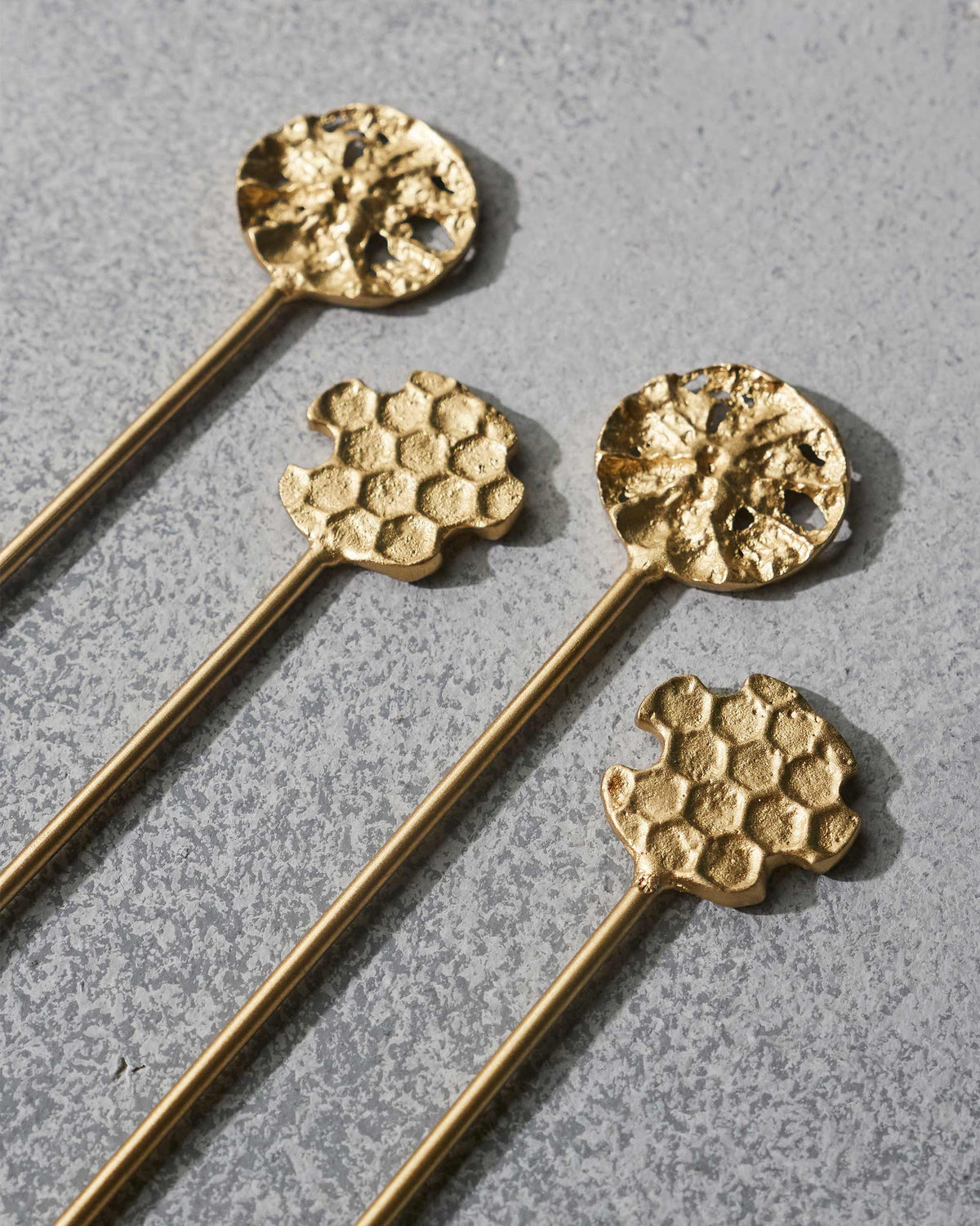 Close-up of gold Dawa stirrers showing their textured honeycomb heads.