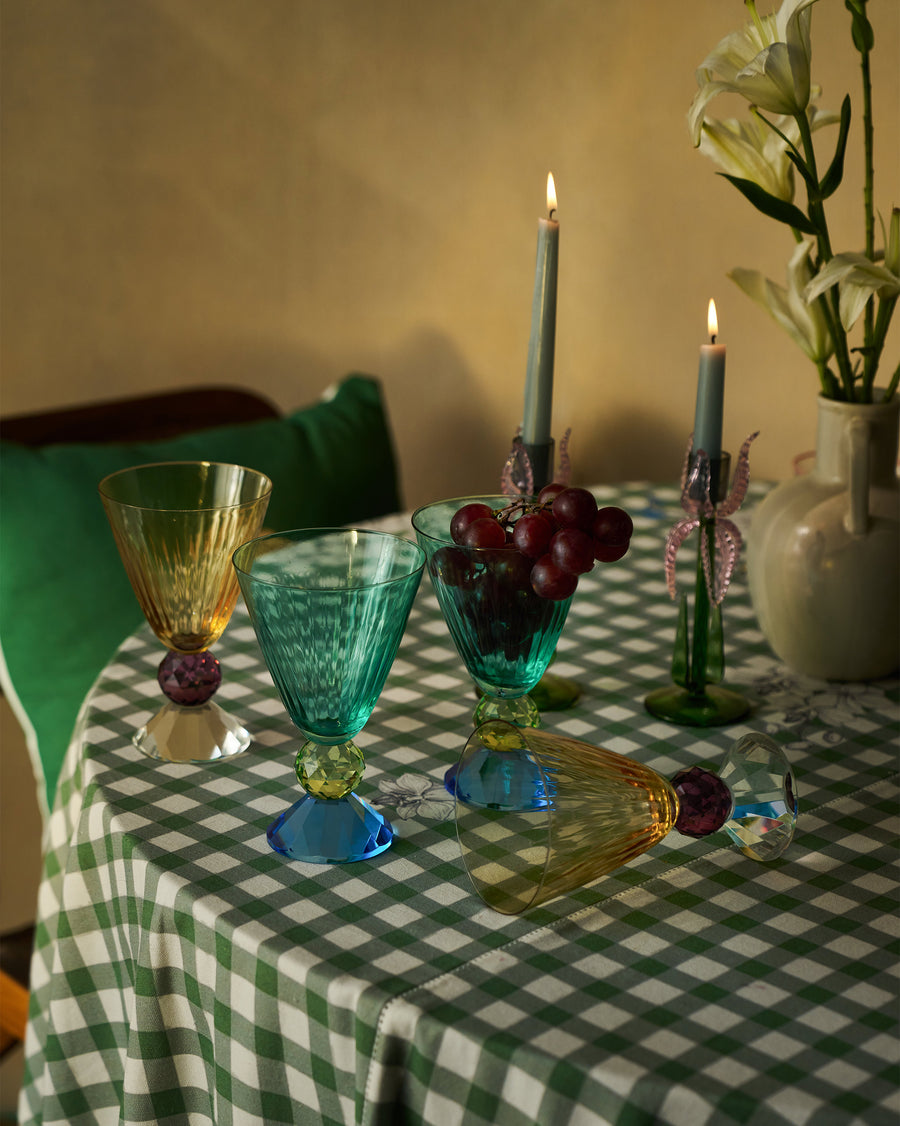 Vira glasses on a green gingham table with grapes, taper candles and lilies
