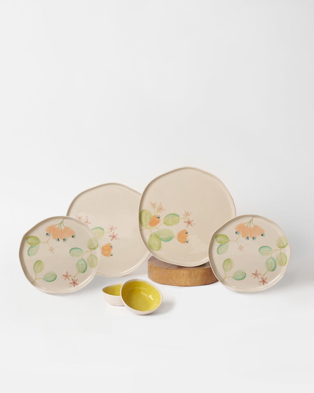 Mandovi dinner set plates with peach buds beside nested yellow bowls.
