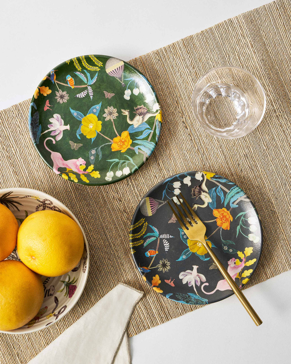 Emerald and charcoal Myra quarter plates with botanical wildlife prints on a table.