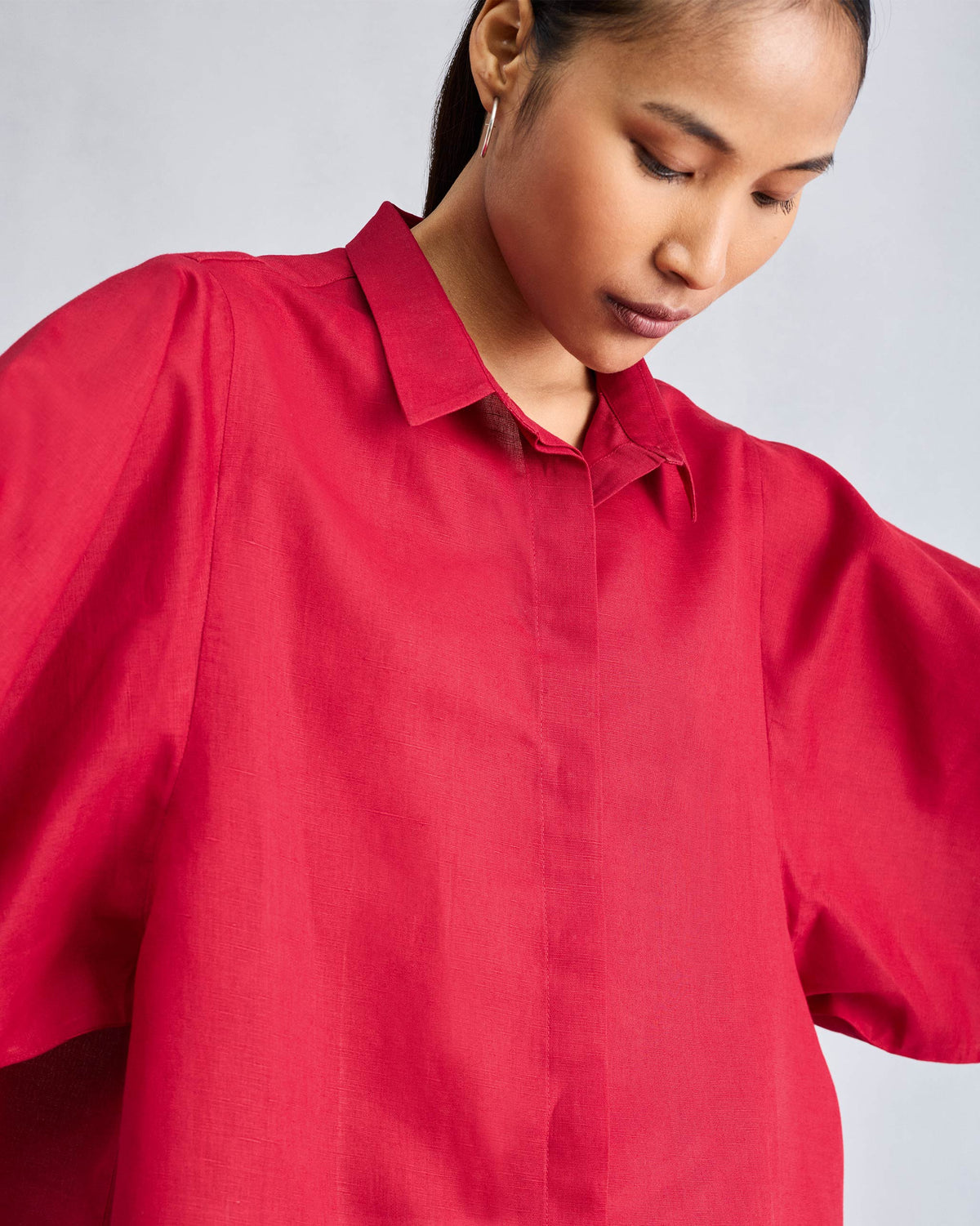 Close-up of the red Drop Armhole shirt showing its collar and wide sleeves.