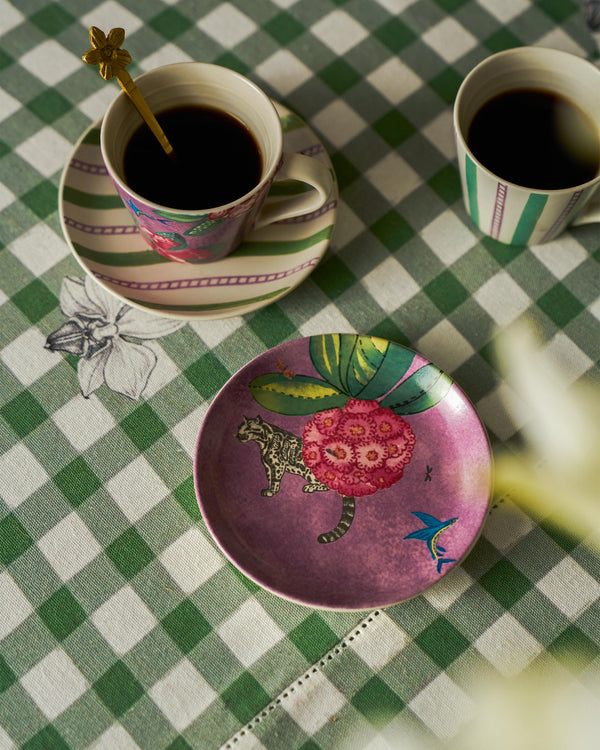 A plate beside coffee cups on gingham