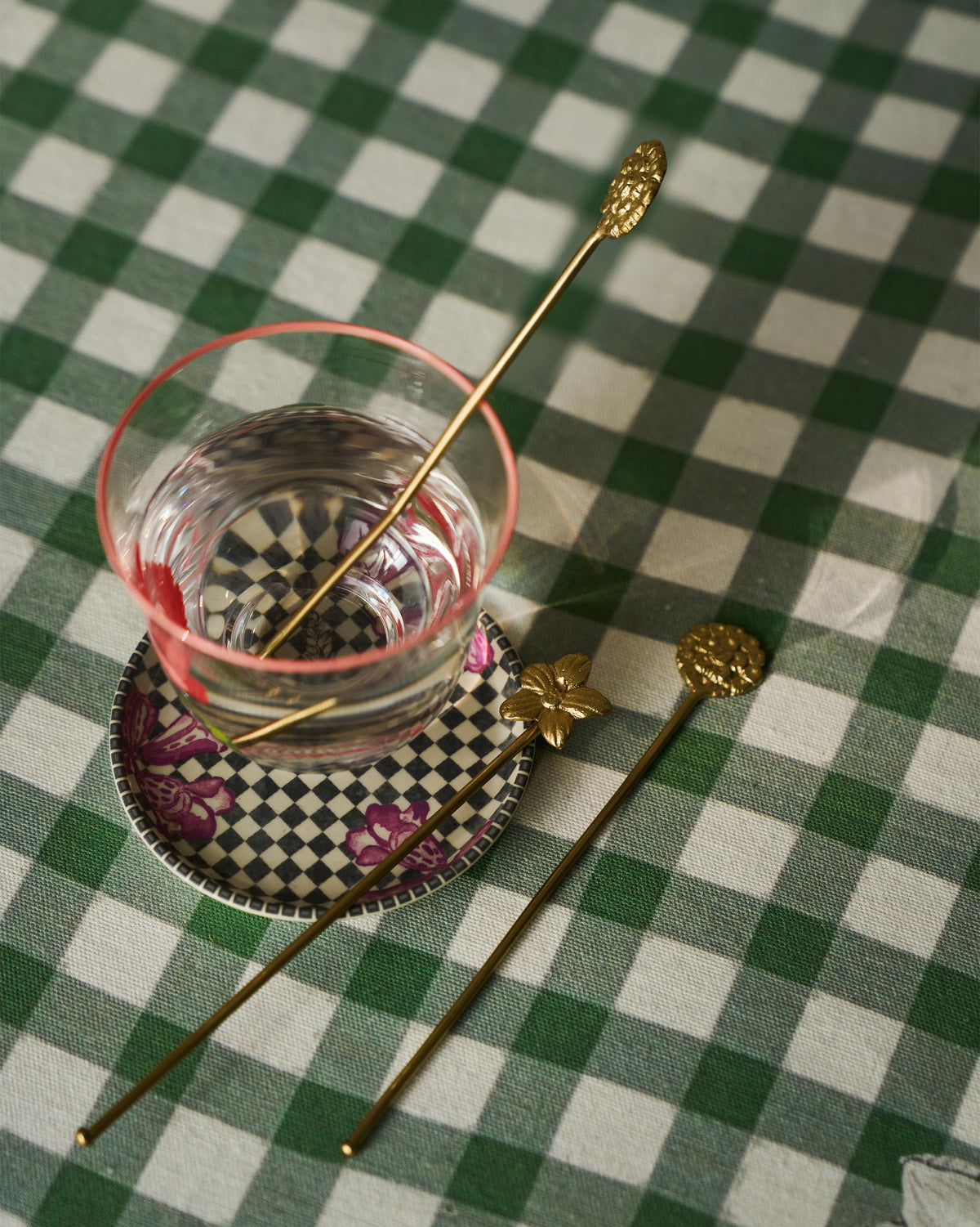 A Bloom stirrer in a glass on a gingham table.