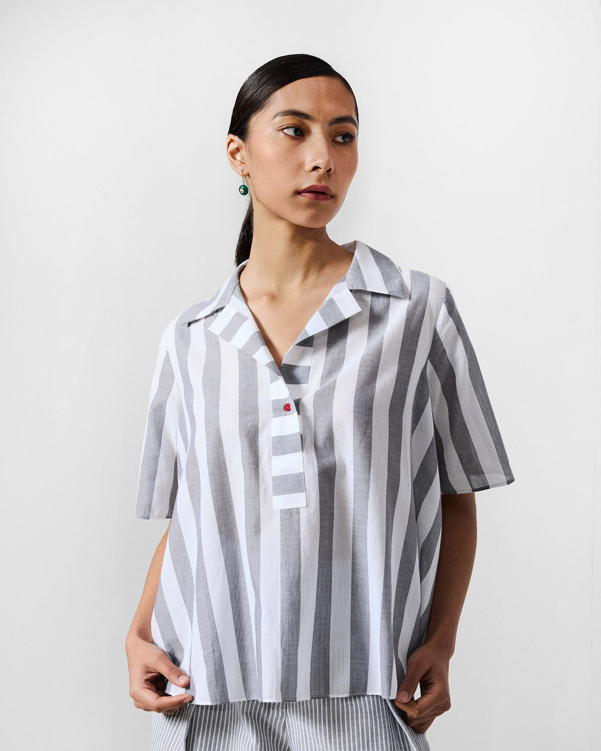 Person wearing a grey and white striped Rann shirt with a red placket accent.