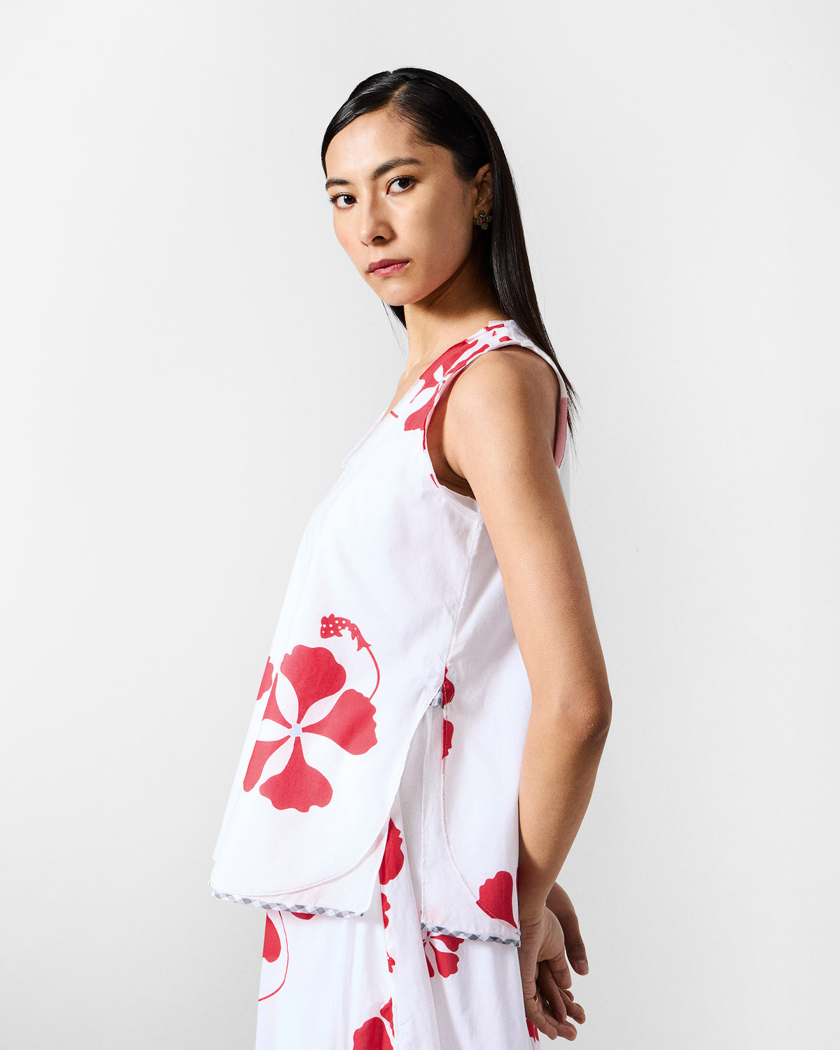 Side view of the Kiva top in white with a red floral print and curved side hem.