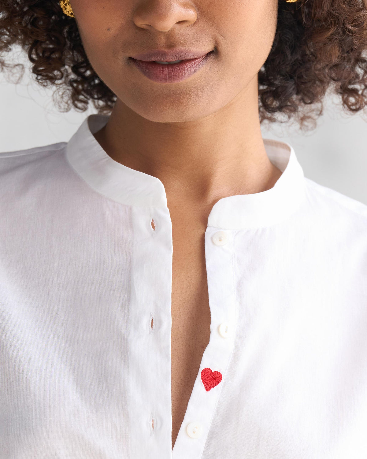 White mandarin collar top with a heart on the placket.