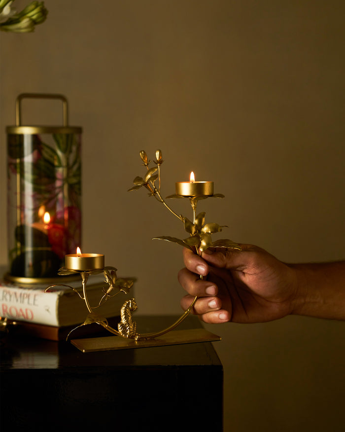 Jasmine Bloom Tealight Holder in gold with two lit tealights, held by a person.