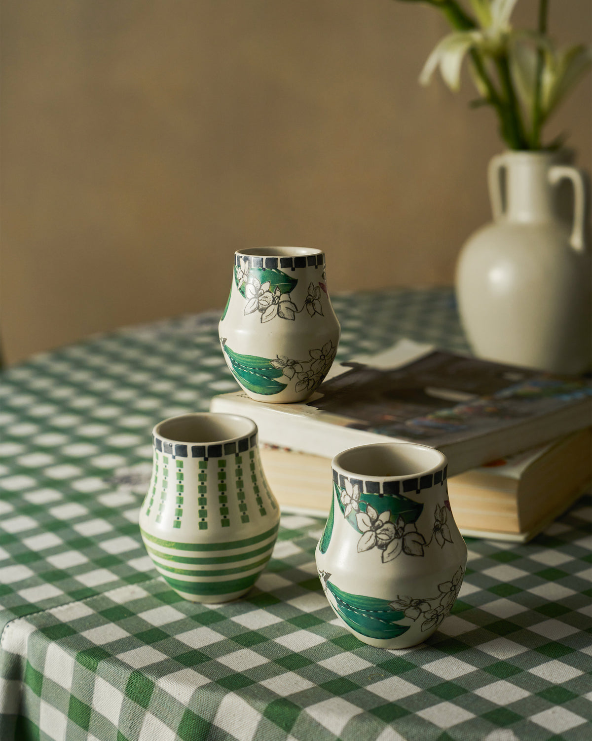 Reesha kulhars with floral and geometric prints on a green checkered cloth.