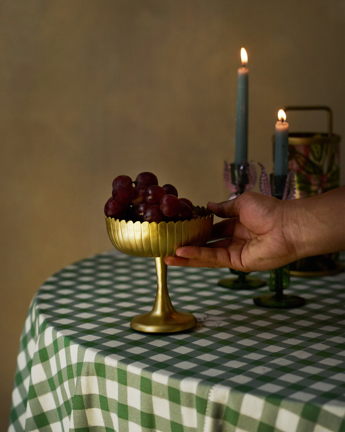 Gold Dhaara serving bowl filled with grapes on a checkered tablecloth.