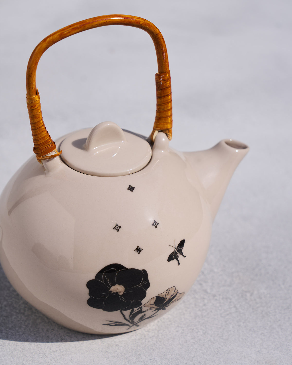 Close-up of Poppy teapot black blooms and wrapped rattan handle.
